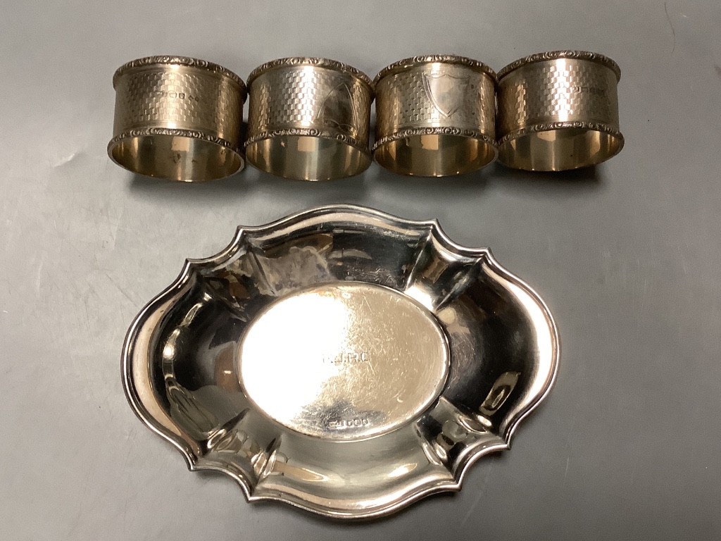 A set of four Edwardian engine turned silver napkin rings, Birmingham 1905, a pair of silver and Ivory mounted knife rests, a silver goblet and a silver dish.